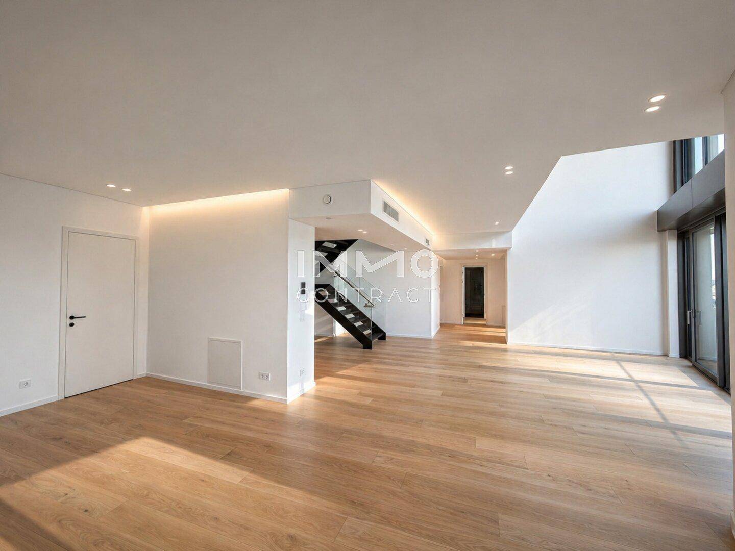 Großer, heller Wohnbereich mit Holzfußboden und viel Tageslicht.