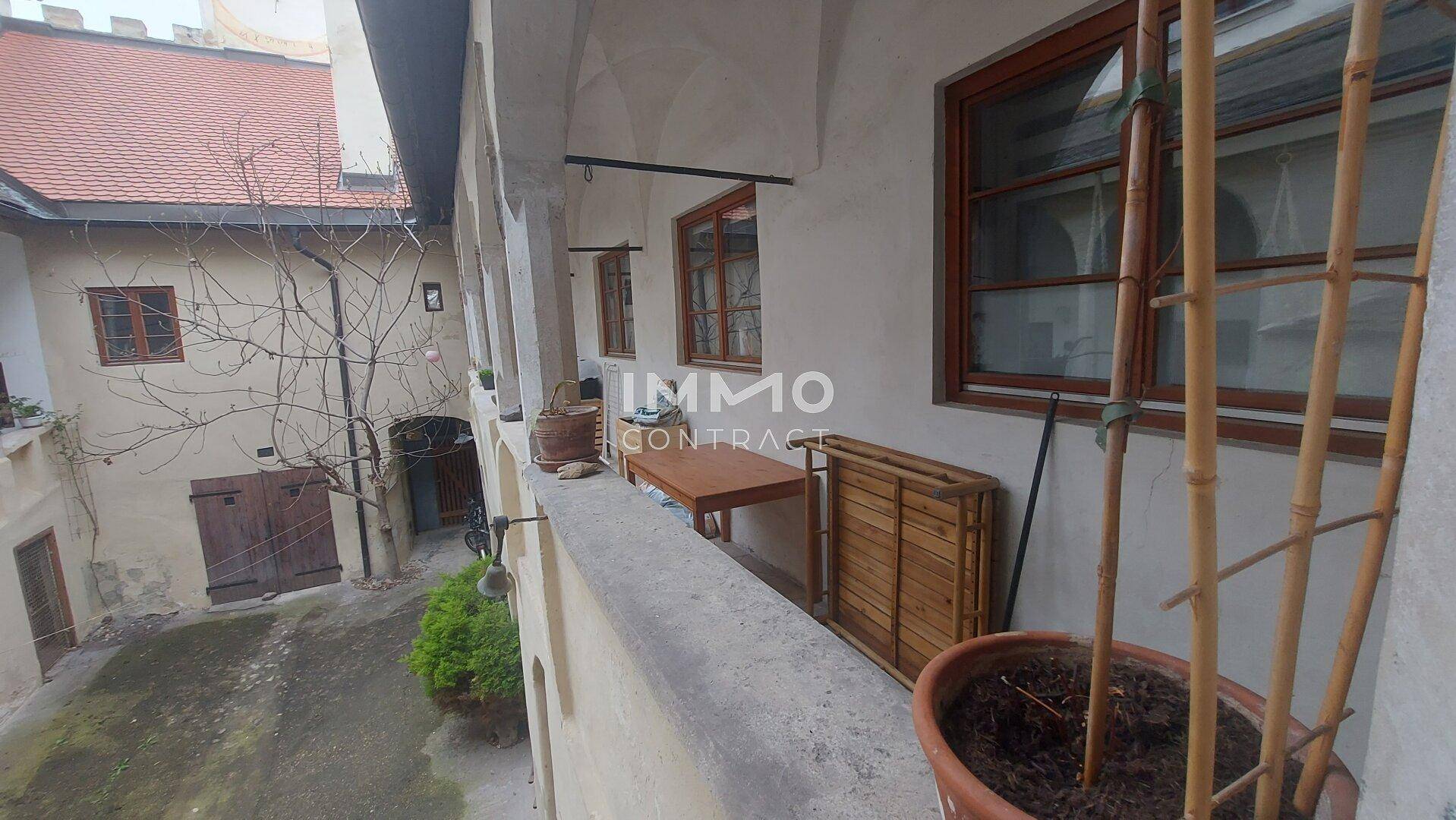 Loggia mit Blick auf den Innenhof, ausgestattet mit einem kleinen Tisch und Pflanzen.