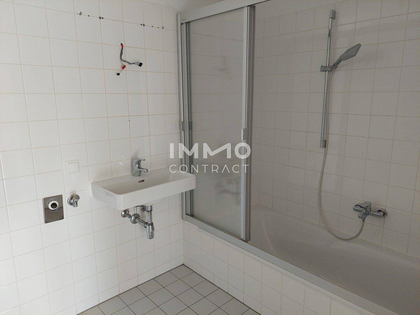 Gefliestes Badezimmer mit Badewanne, Duschvorrichtung und Waschbecken.