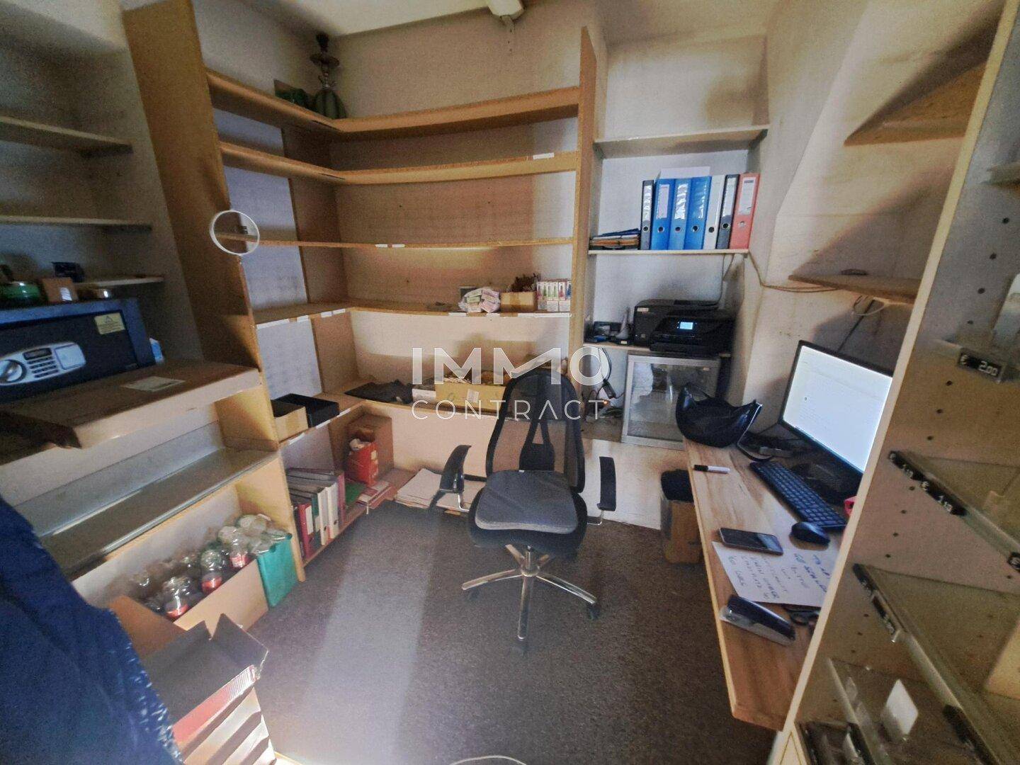 Kleines Büro oder Lagerraum mit vielen Holzregalen, einem Schreibtisch und Bürostuhl.