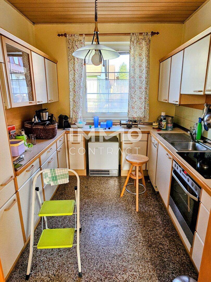Funktionale Küche mit weißen Schränken, Fenster und traditionellem Bodenbelag.