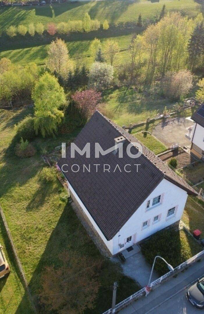 Luftaufnahme des Einfamilienhauses mit umliegendem Garten und angrenzender Straße.