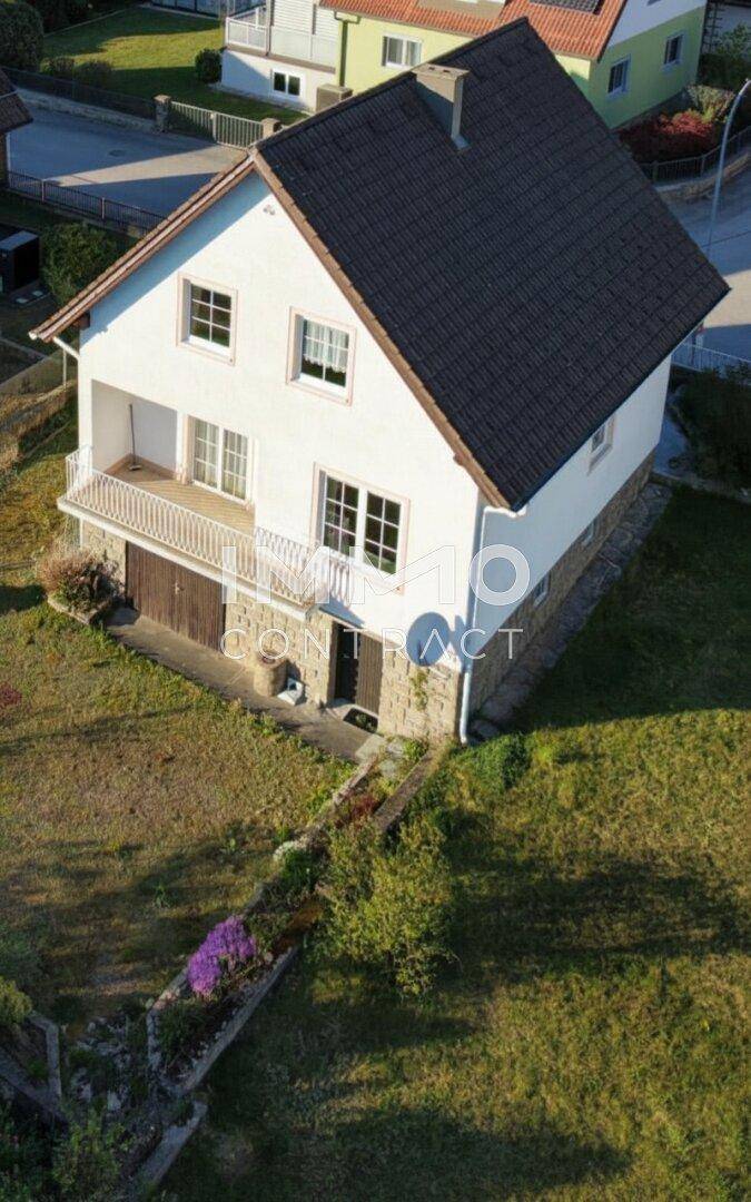 Luftaufnahme des Hauses mit Balkon, Garage und gepflegtem Gartenbereich.