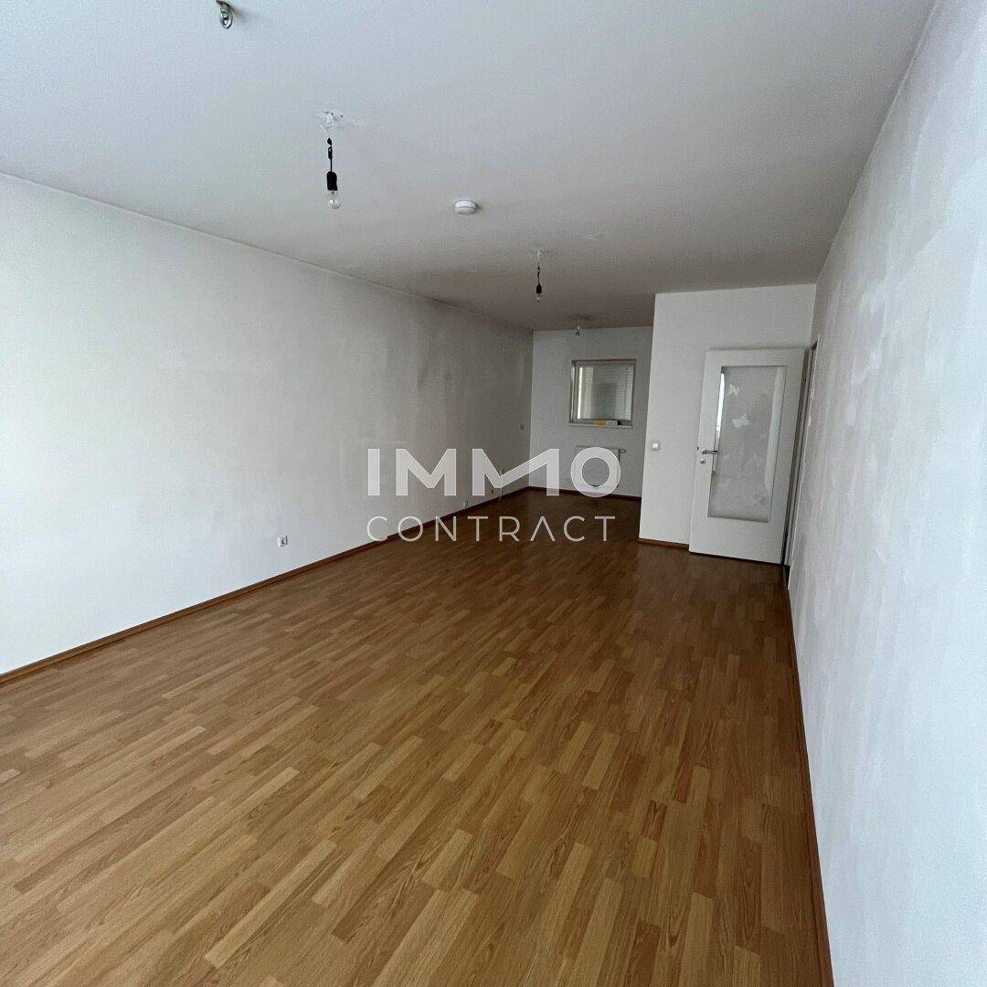 Geräumiger, leerer Raum mit Laminatboden und weiß gestrichenen Wänden, ideal für individuelle Gestaltung.