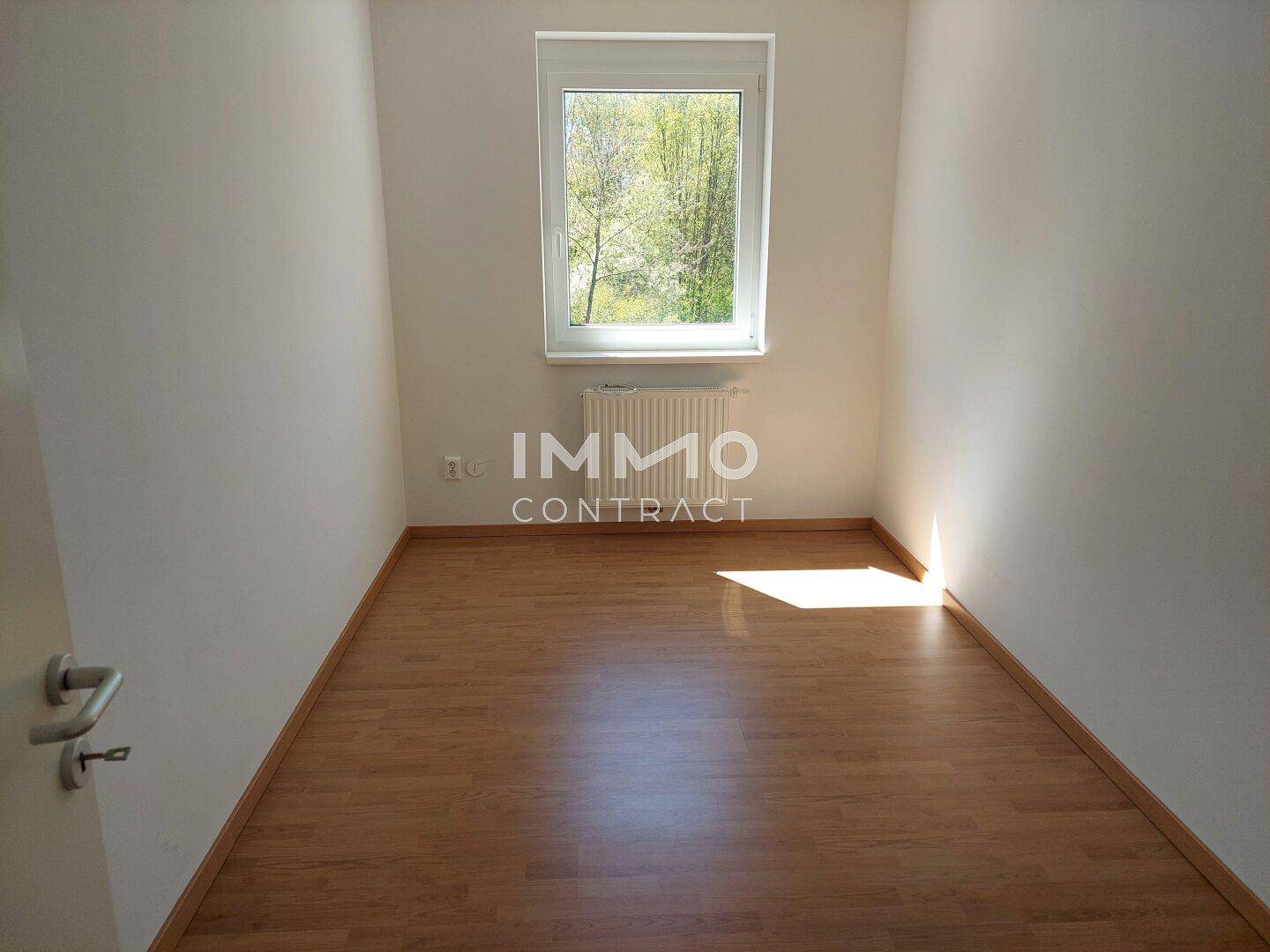 Heller Raum mit Holzboden, Fenster und Heizkörper, ideal für ein Kinderzimmer oder Büro.
