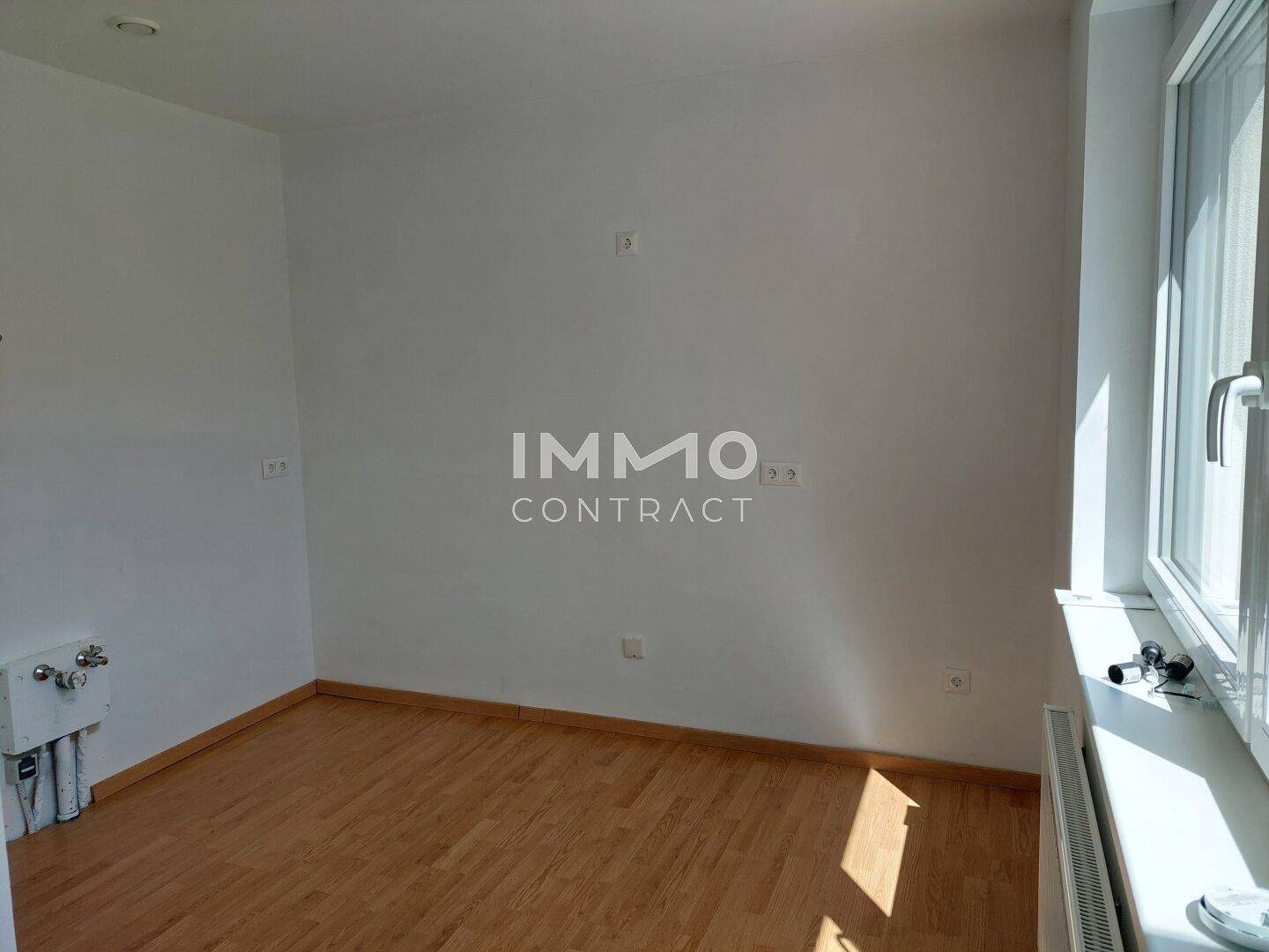 Kleiner, heller Raum mit Fenster, Heizkörper und Anschlüssen für Waschmaschine oder Abstellraum.