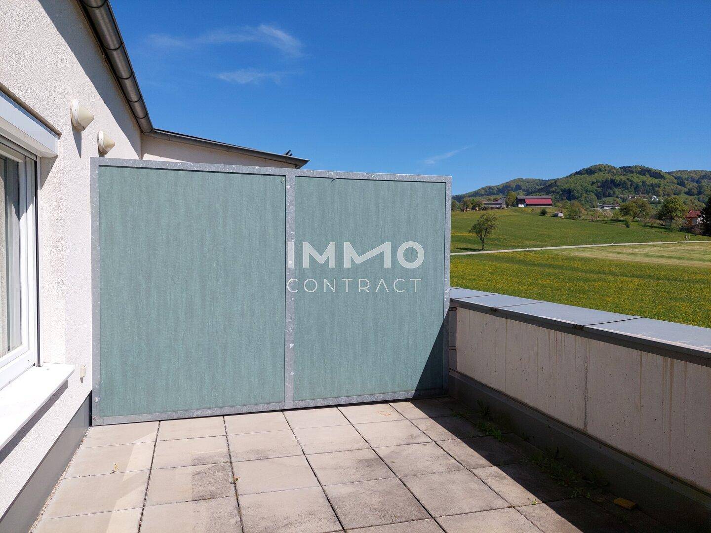 Geräumige Terrasse mit Fliesenboden, Sichtschutz und weitem Blick über die grüne Landschaft.