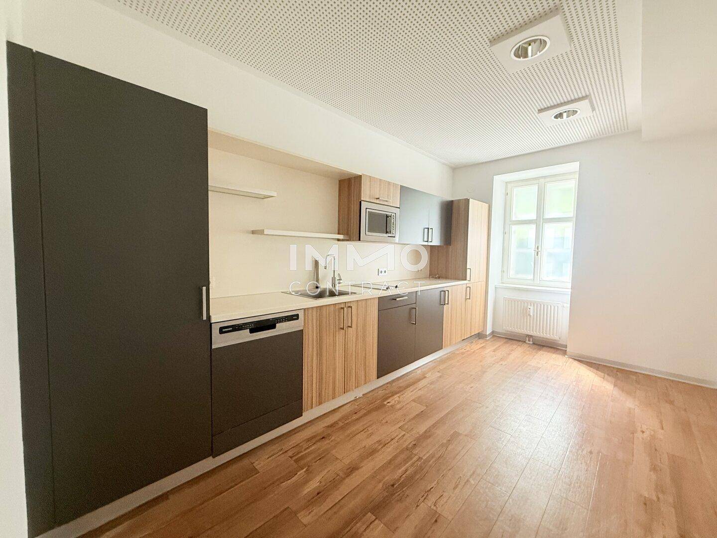Moderne Küchenzeile mit Holz- und Anthrazitfronten, ausgestattet mit Spülmaschine und Mikrowelle, mit Fenster.