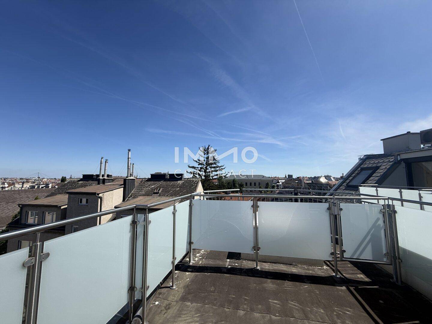 Weitläufige Dachterrasse mit Blick auf die umliegenden Gebäude und den blauen Himmel.