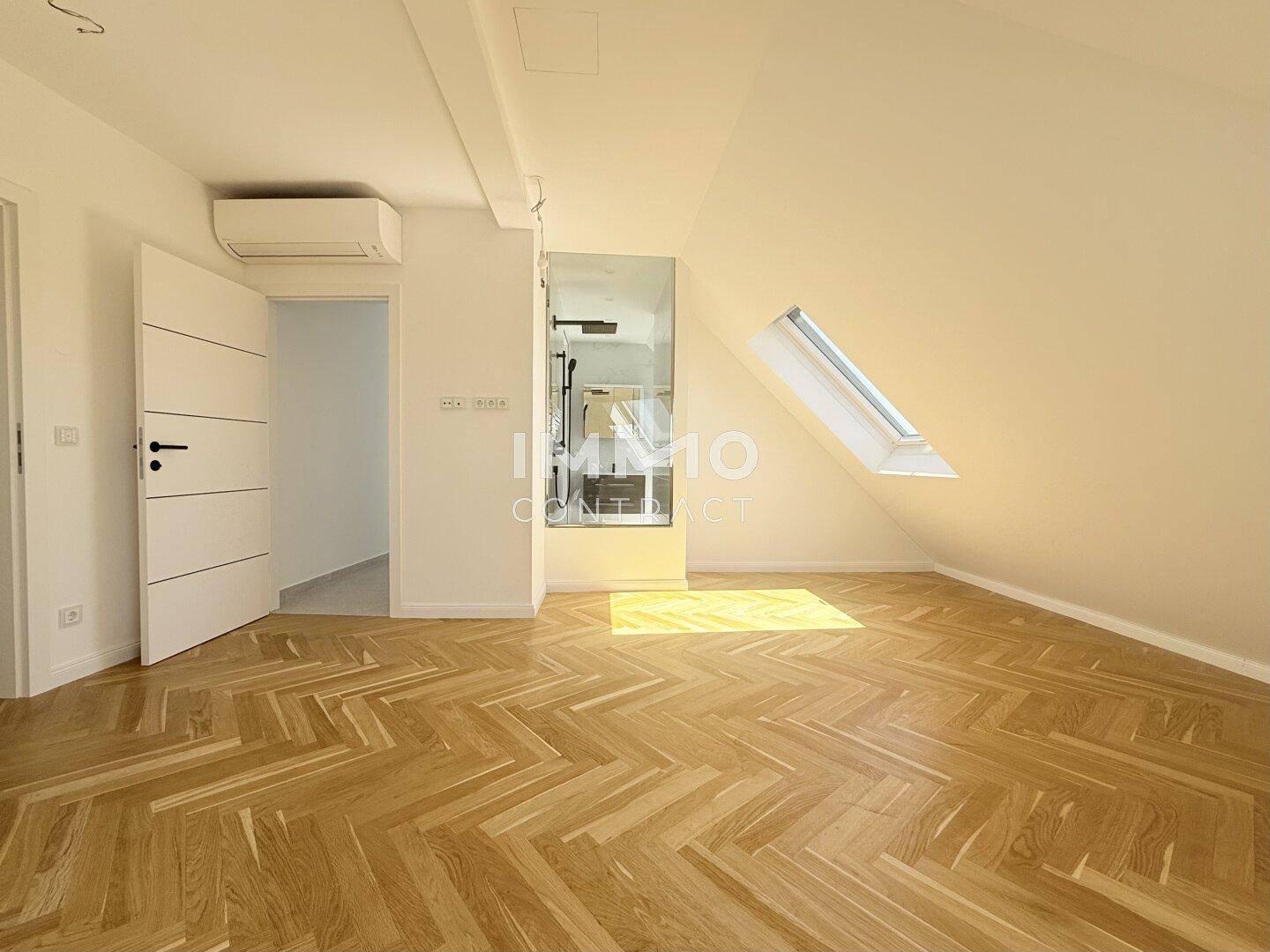 Helles Schlafzimmer mit Fischgrätparkett, Dachschräge, Klimaanlage und einem Dachfenster.