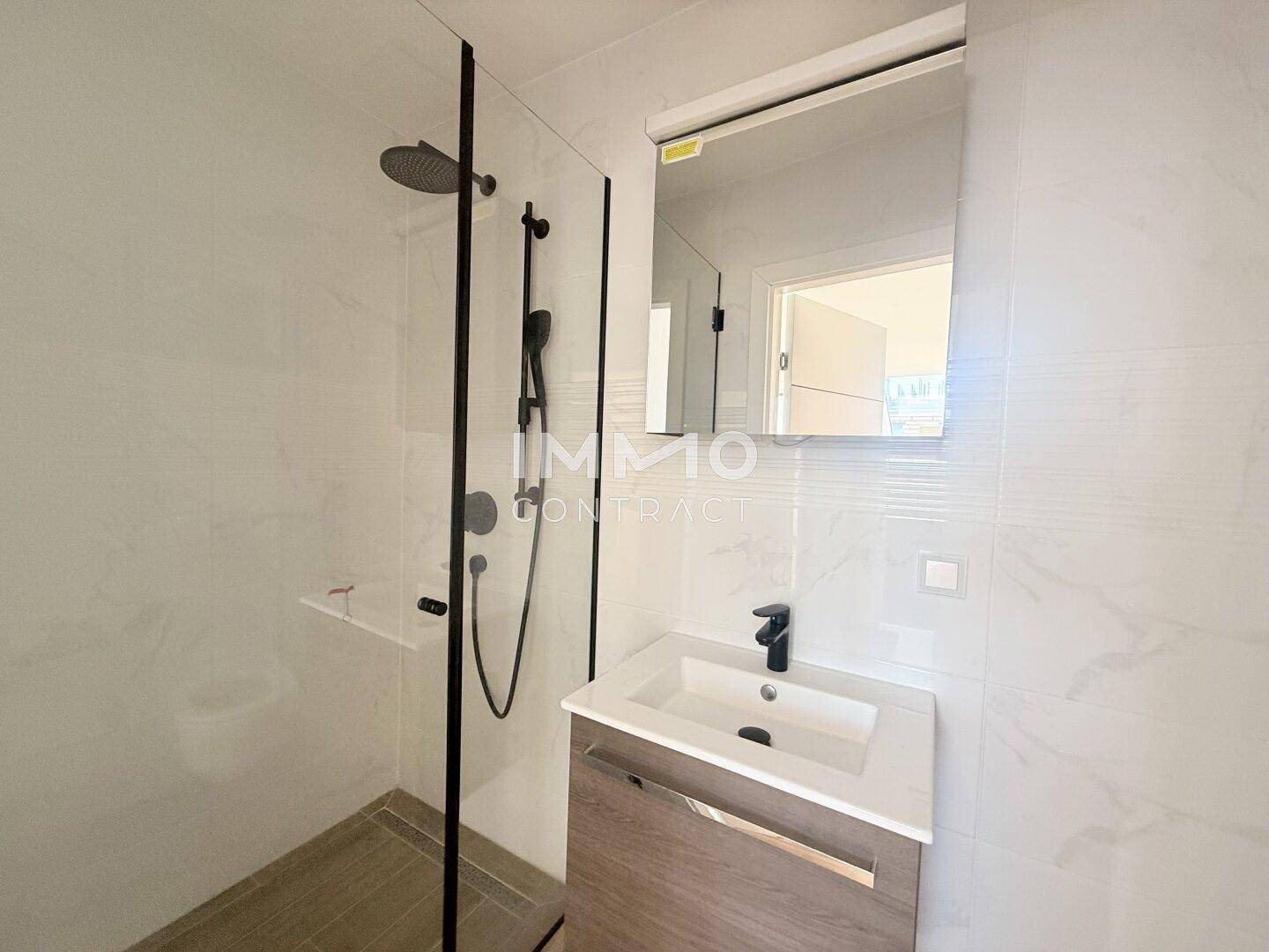 Modernes Badezimmer mit begehbarer Dusche, Waschtisch und weißen Fliesen.