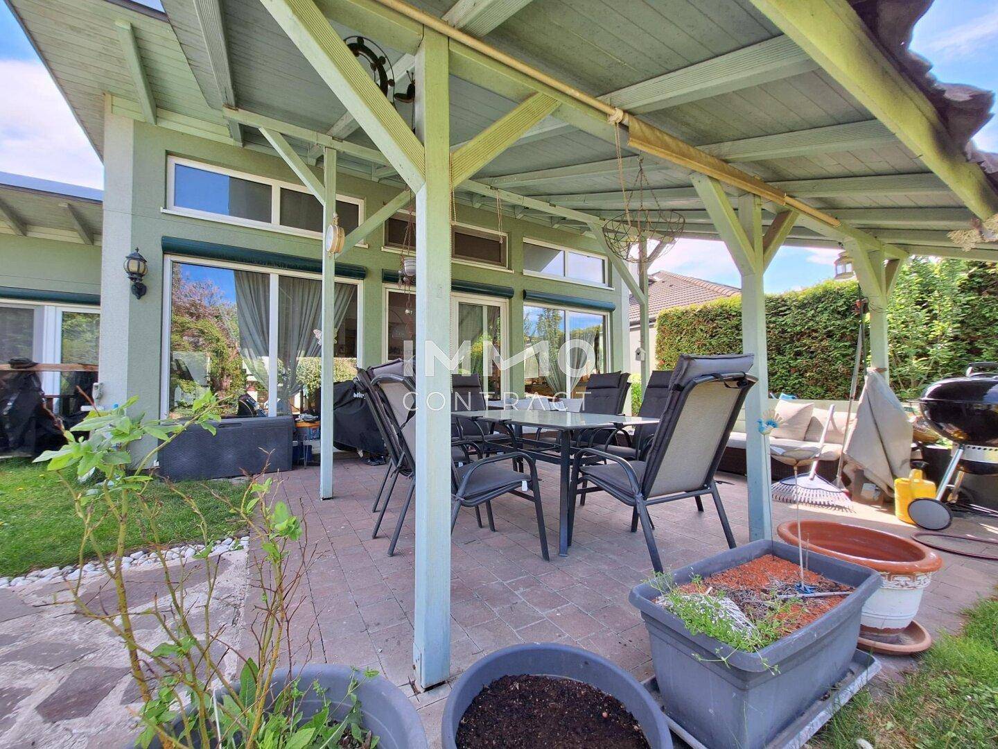 Überdachte Terrasse mit Esstisch und Stühlen, ideal für Mahlzeiten im Freien.