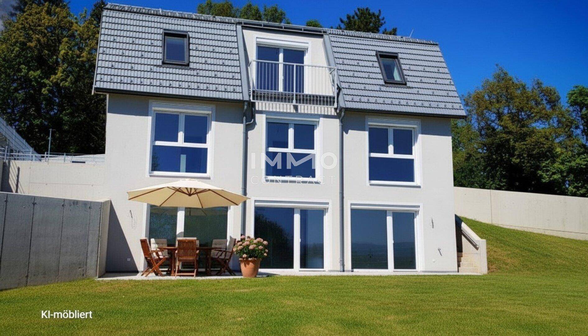 Rückseite des Hauses mit möblierter Terrasse, Sonnenschirm und Zugang zum grünen Garten.
