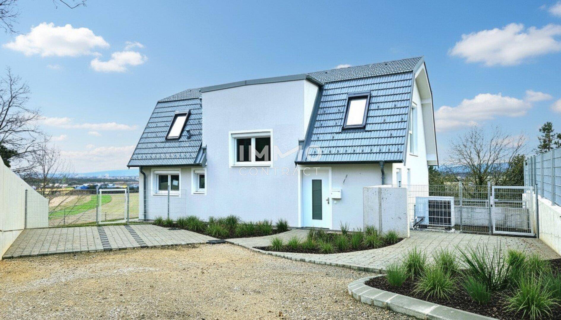Vorderansicht des modernen Hauses mit Eingangsbereich, Zufahrt und Stellplätzen.