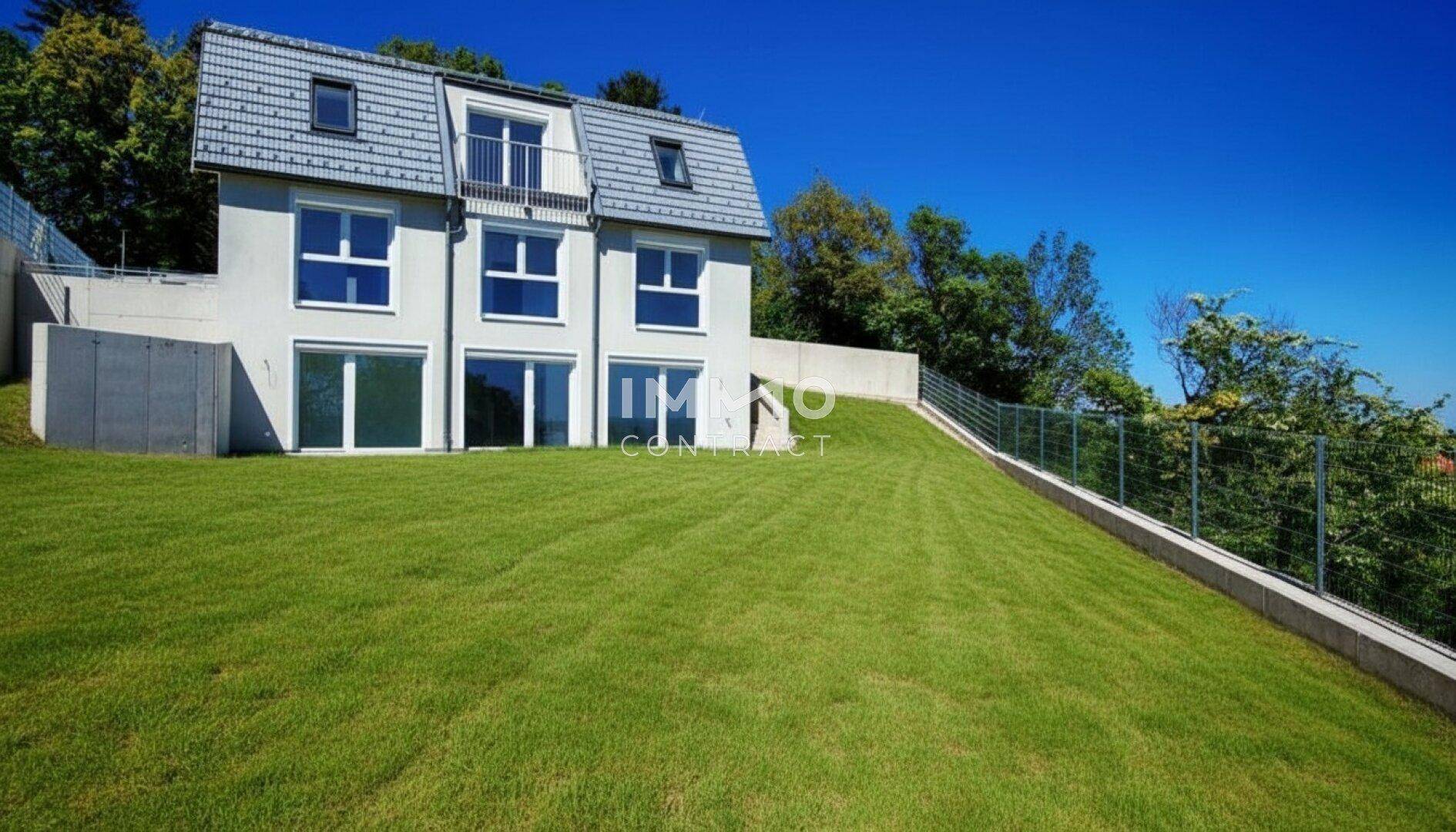 Modernes Einfamilienhaus auf einem weitläufigen Grundstück mit grüner Rasenfläche.