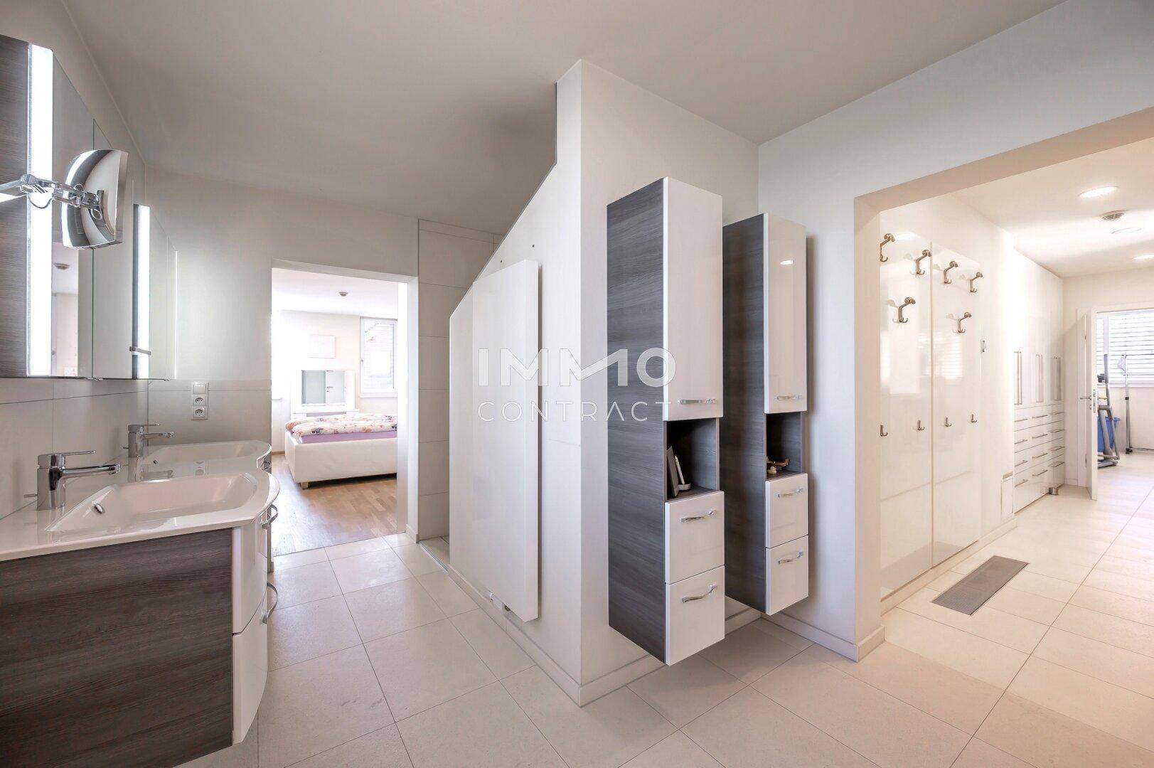 Helles Badezimmer mit Waschbecken und Schränken, angrenzend an Schlafzimmer und Flur.
