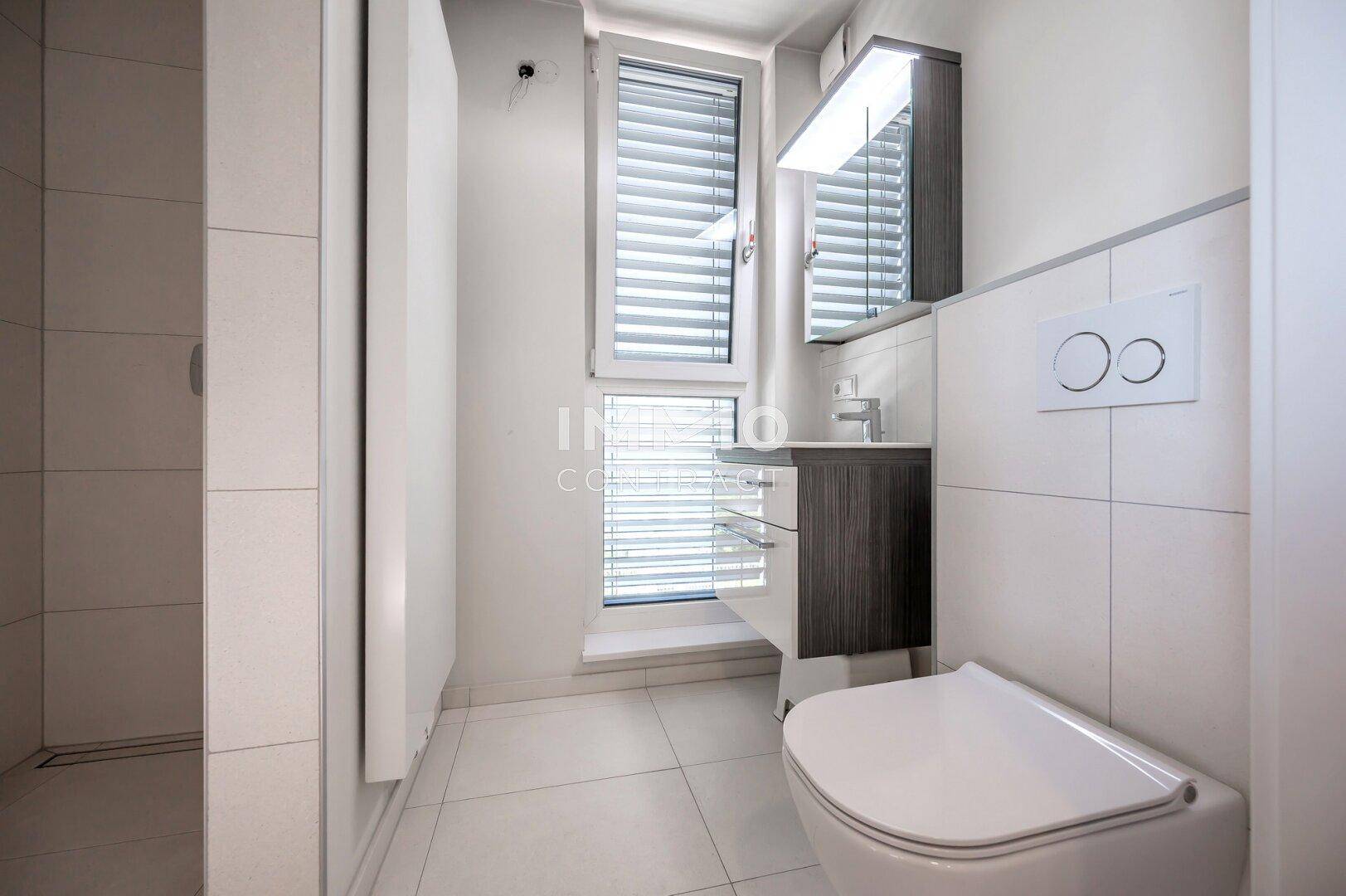 Modernes Badezimmer mit wandhängender Toilette, Waschbecken und Duschbereich.