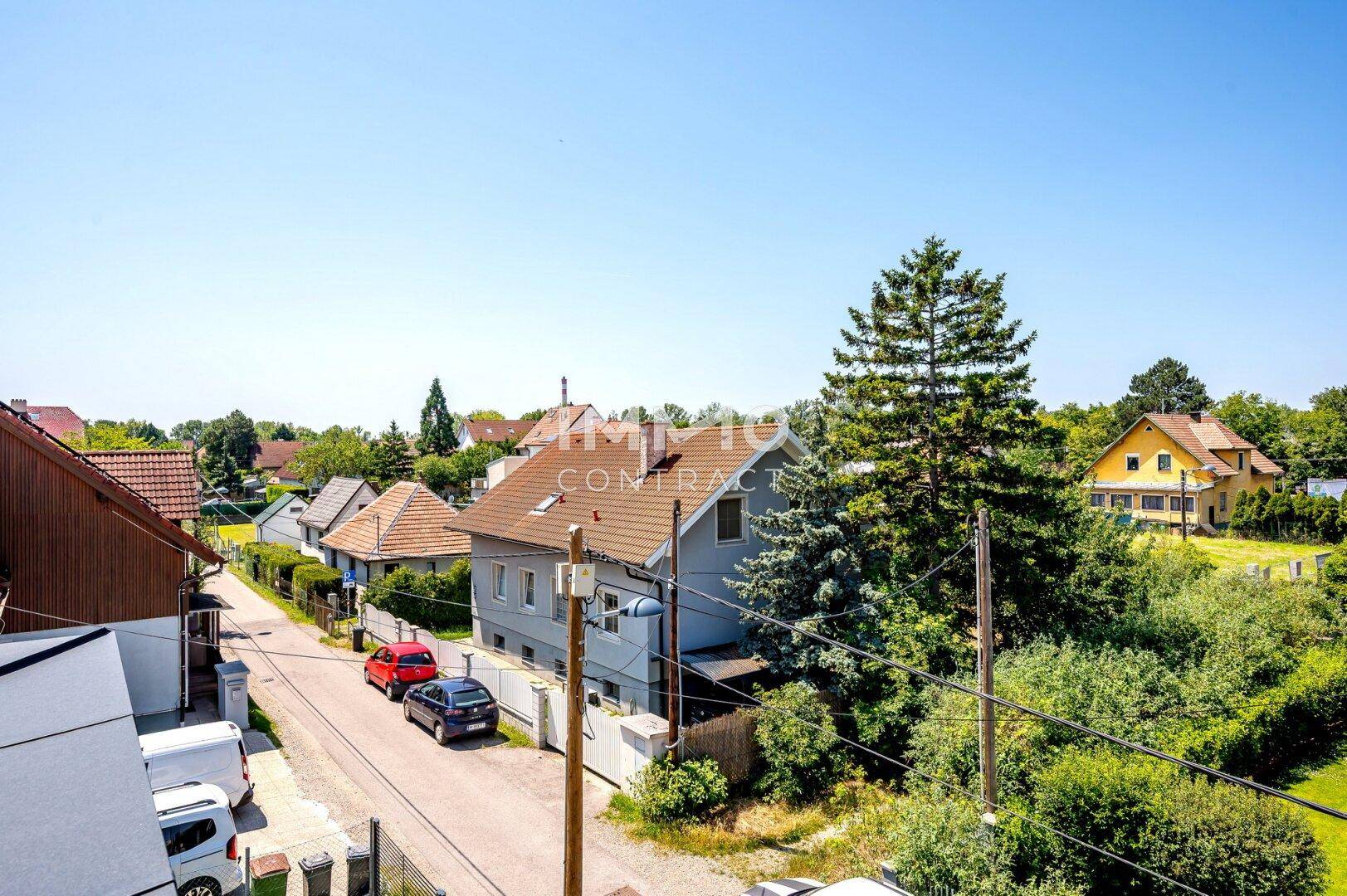 Blick über eine ruhige Wohnstraße mit Einfamilienhäusern und viel Grün.