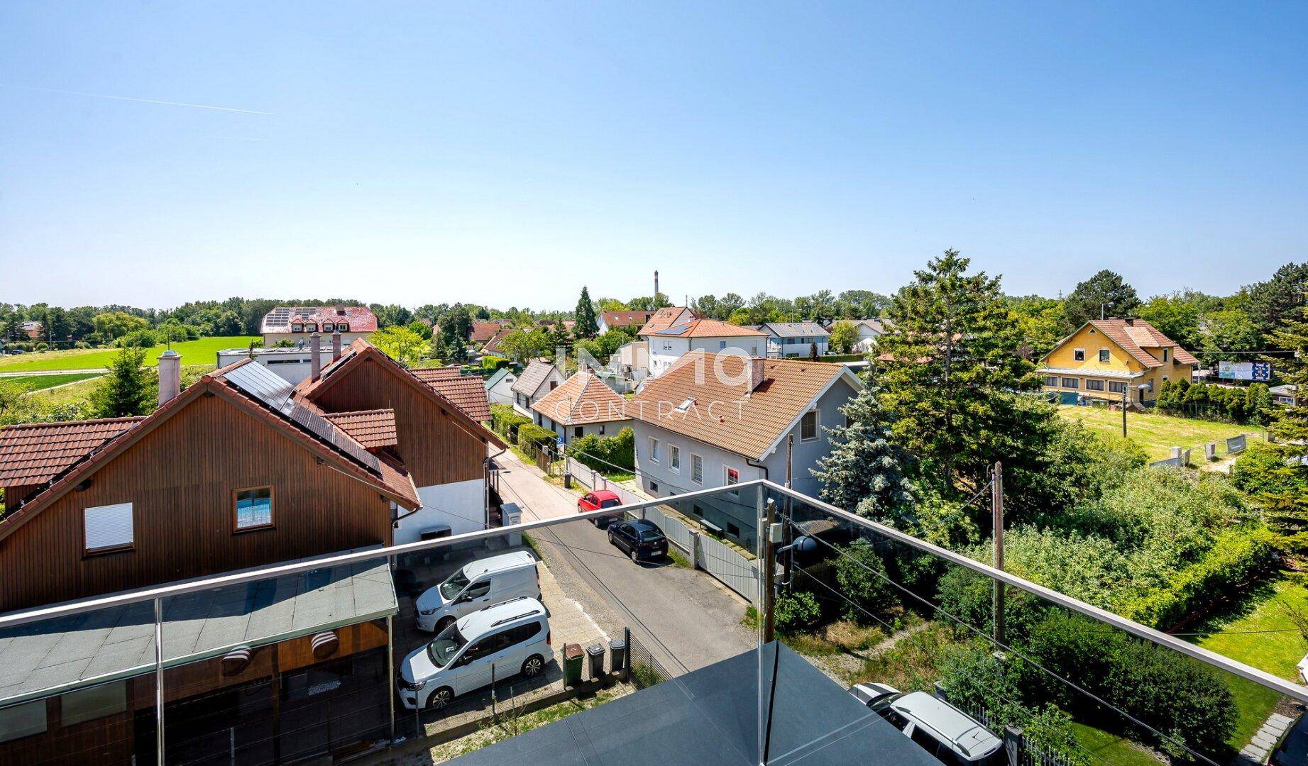 Blick von oben auf eine Wohnstraße mit geparkten Autos und umliegenden Häusern.