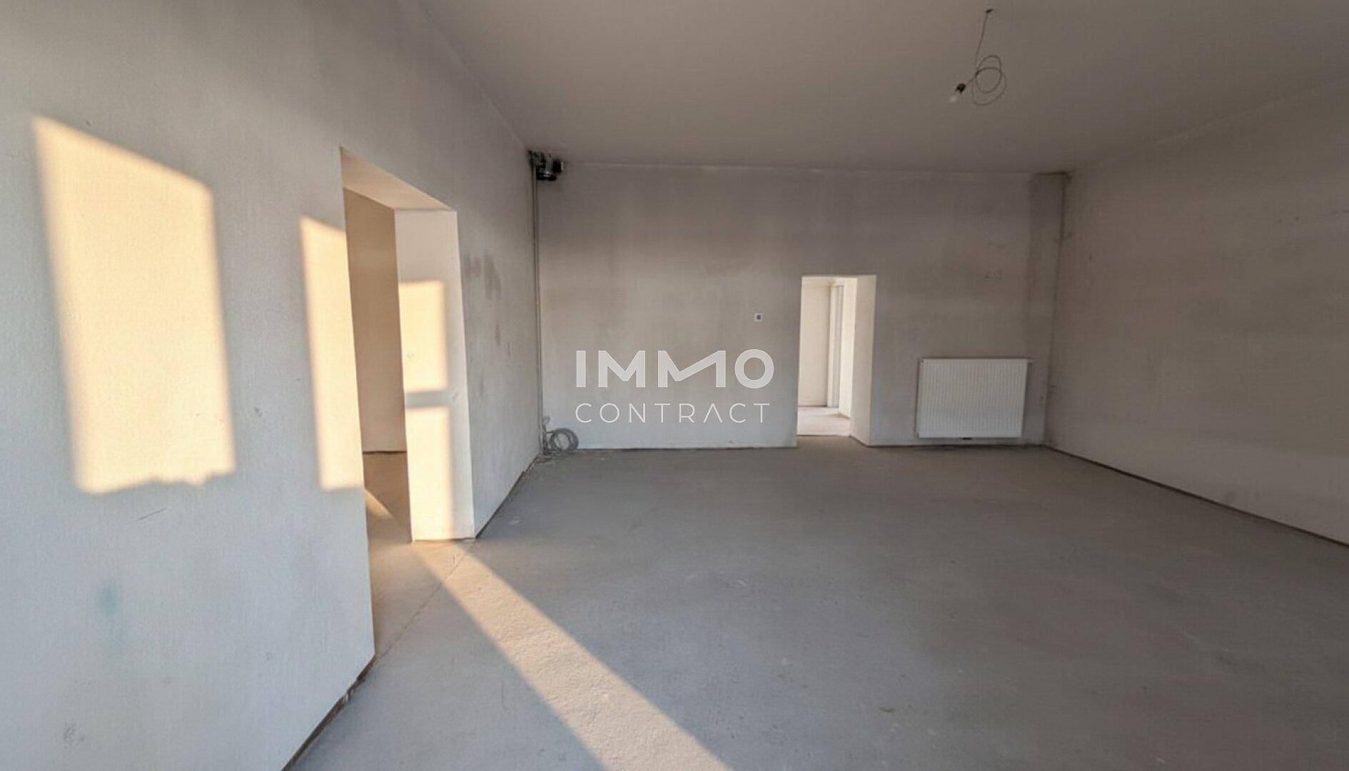 Heller, leerer Innenraum mit Betonboden und unverputzten Wänden, der viel natürliches Sonnenlicht empfängt.