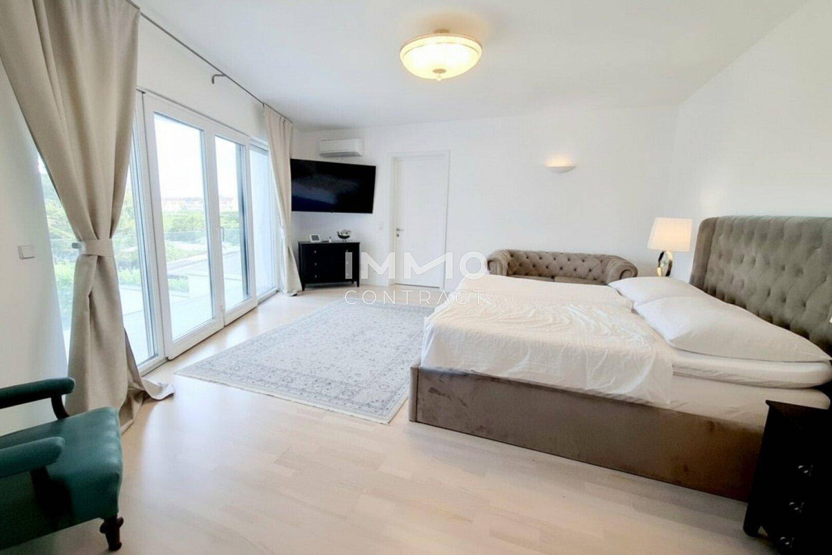 Helles Schlafzimmer mit großem Bett, Holzboden und direktem Zugang zum Balkon.