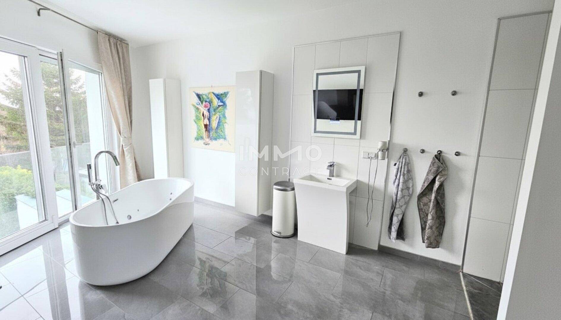 Modernes Badezimmer mit freistehender Badewanne, großen Fenstern und eleganten Fliesen.