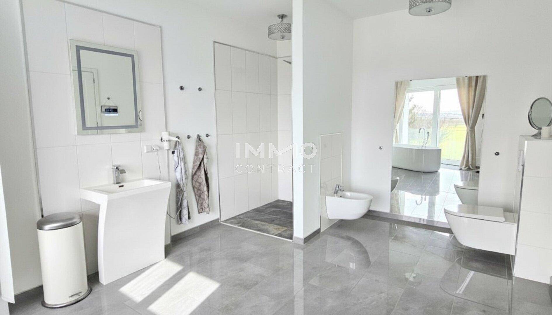 Geräumiges Badezimmer mit begehbarer Dusche, Bidet, WC und modernem Waschtisch.