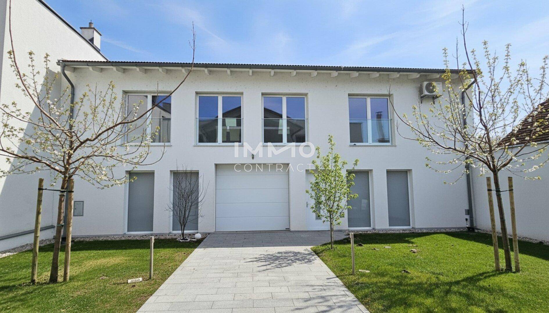 Vorderansicht des modernen Hauses mit integrierter Garage und gepflegter Auffahrt.