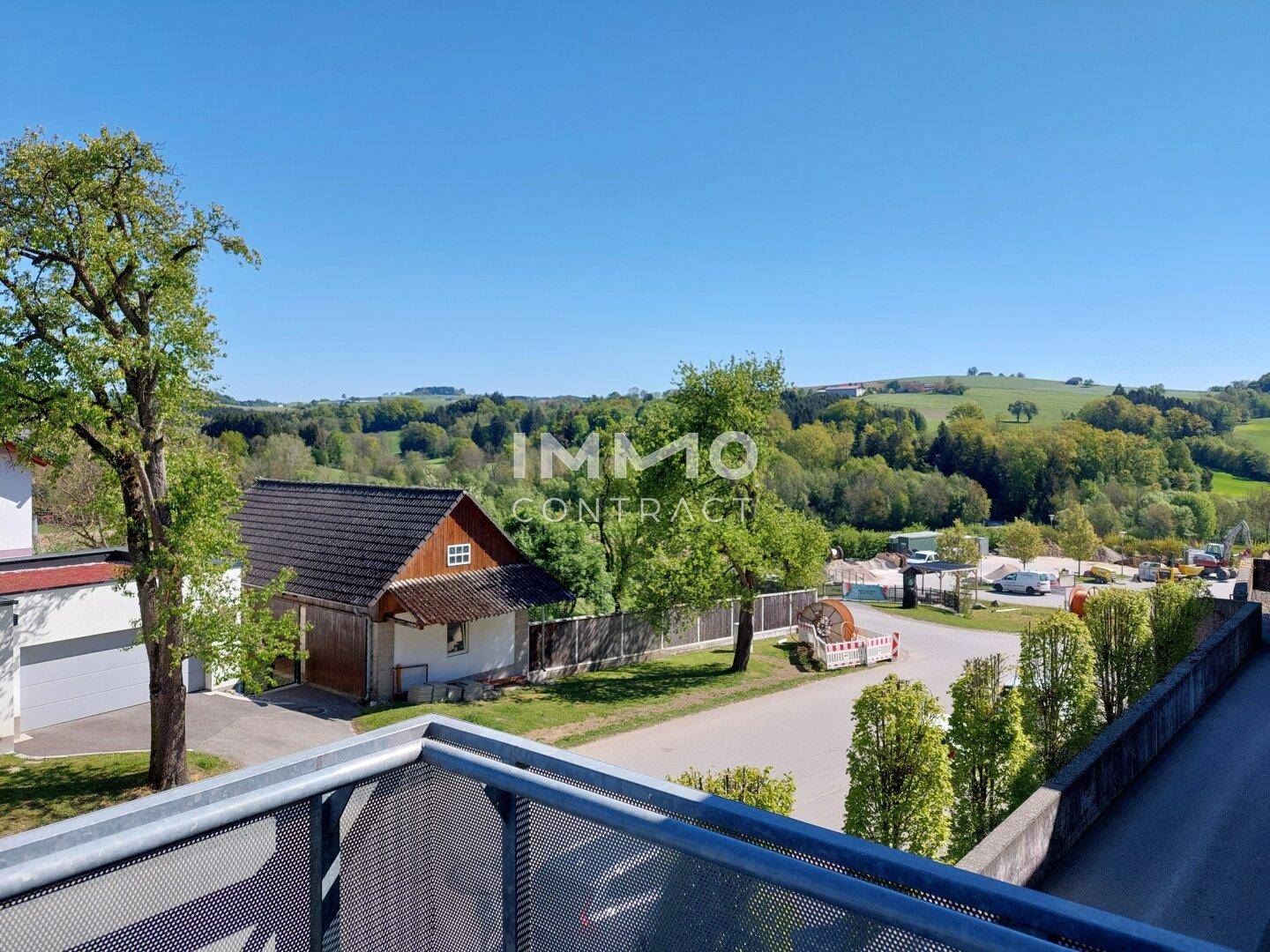 Weitläufiger Blick vom Balkon auf die grüne Hügellandschaft und umliegende Natur.