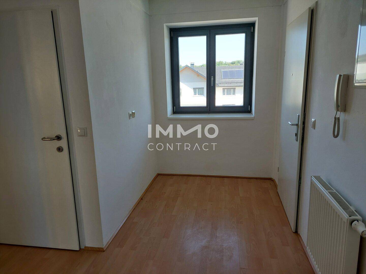 Heller Flur mit Fenster, Heizkörper und Zugang zu weiteren Räumen.