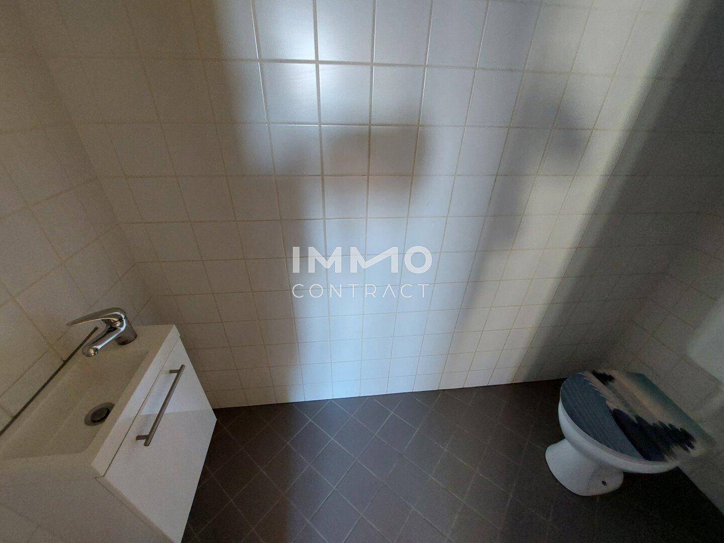 Kleines WC mit Toilette, Waschbeckenunterschrank und weißen Wandfliesen.