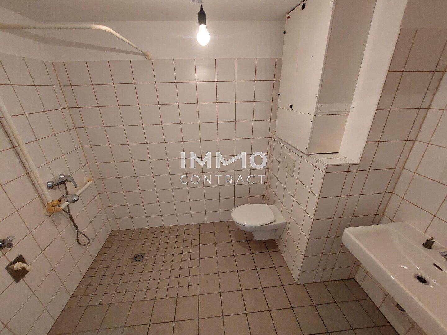 Funktionales Badezimmer mit Fliesen an Wänden und Boden, Toilette und Waschbecken.