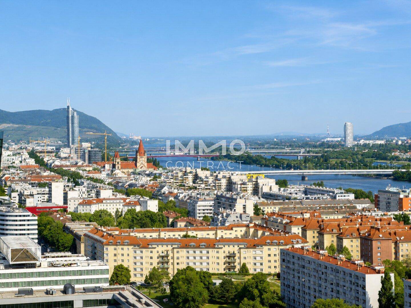 Weitläufiger Stadtblick mit Fluss, Brücken und markanten Gebäuden unter blauem Himmel.