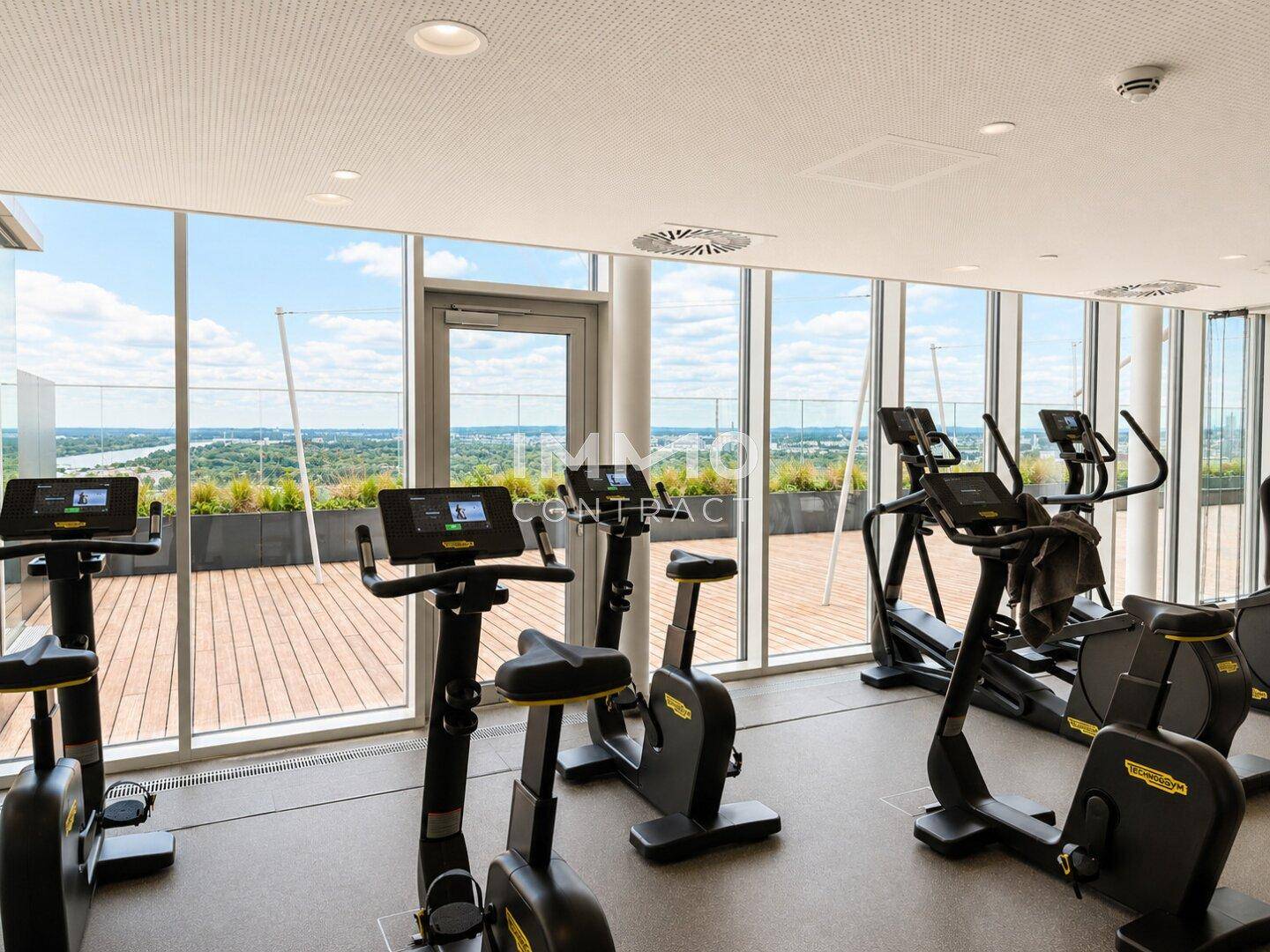 Fitnessraum mit modernen Geräten und großen Fenstern, die einen weiten Blick bieten.