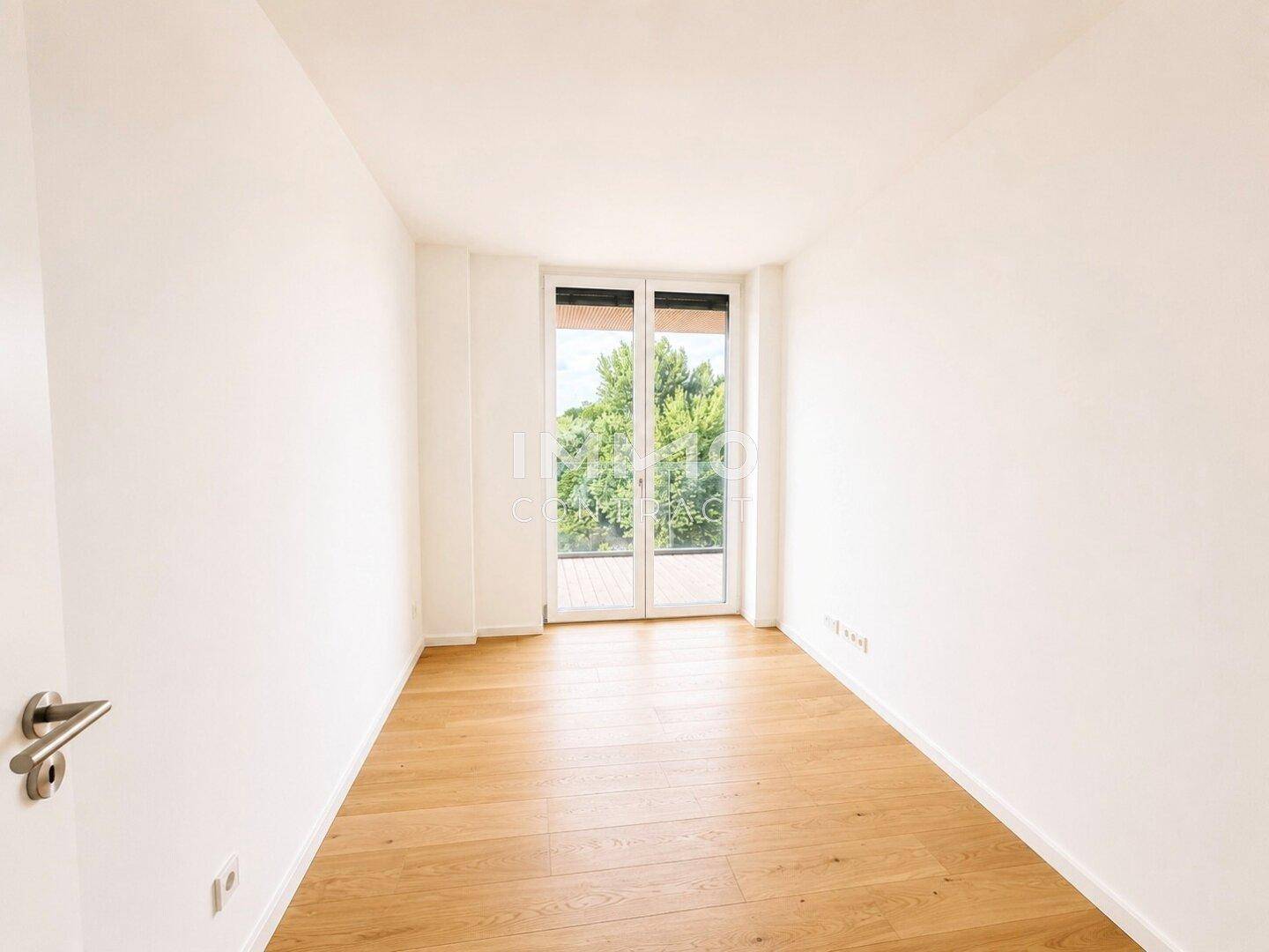 Helles, unmöbliertes Zimmer mit Parkettboden und Zugang zum Außenbereich.