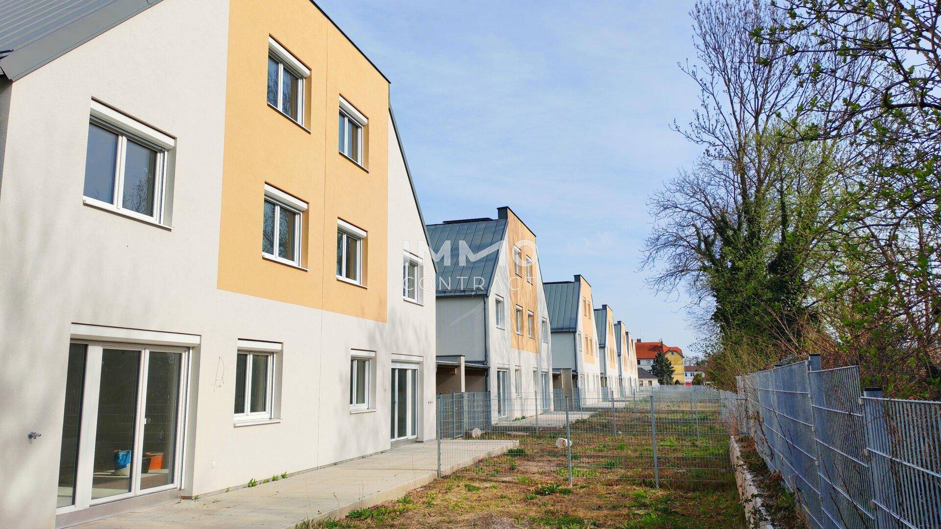 Weitere Ansicht der modernen Reihenhäuser mit gelben Fassadenakzenten und Satteldächern.