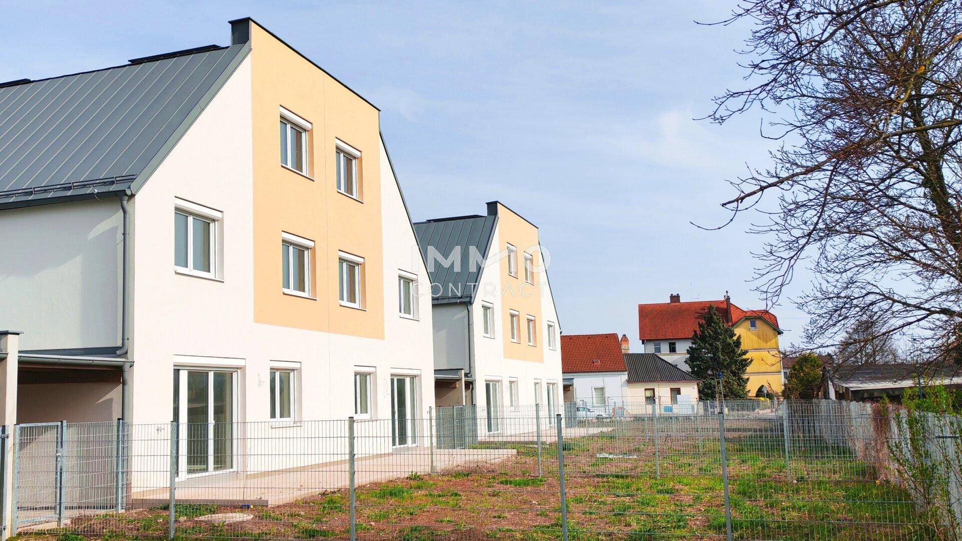 Eine Reihe von modernen Reihenhäusern mit Gärten und Blick auf die Umgebung.