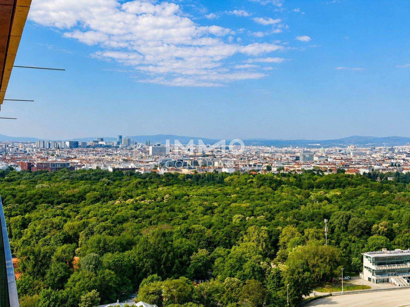 Panoramablick über eine weitläufige Grünfläche und die Skyline der Stadt unter blauem Himmel.