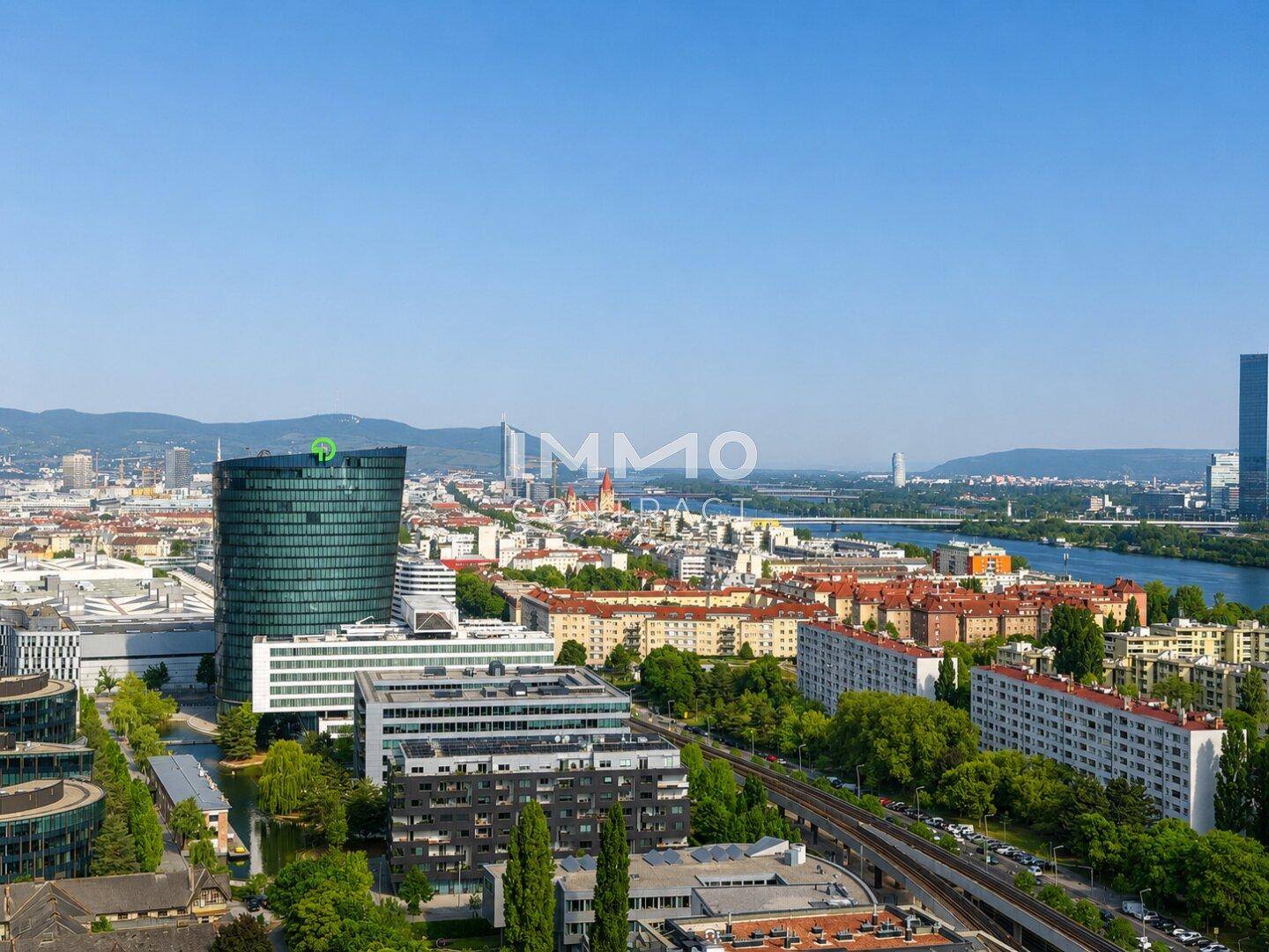 Panoramablick auf die Stadt mit modernen Gebäuden und dem Fluss unter strahlend blauem Himmel.