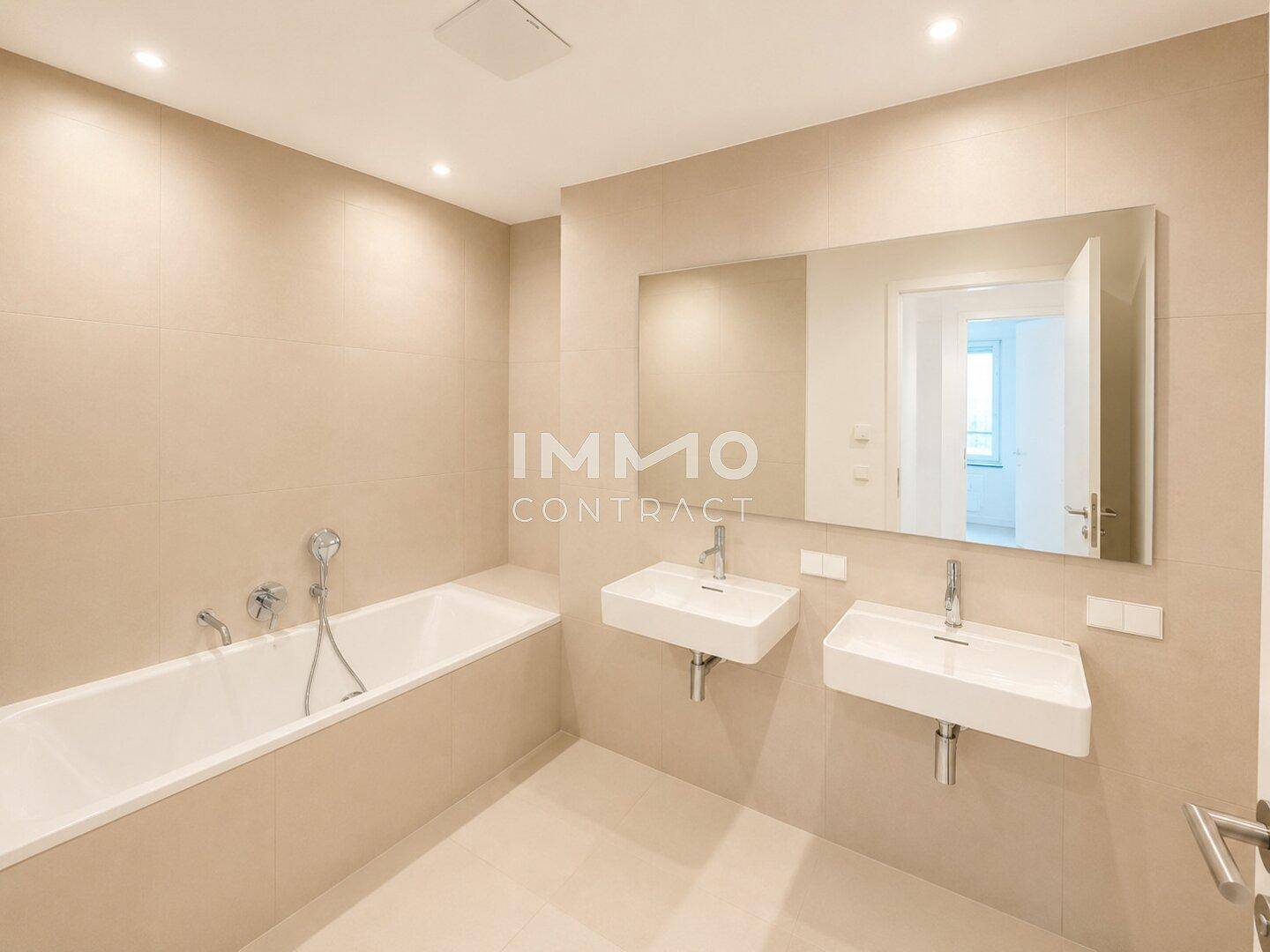 Modernes Badezimmer mit beigefarbenen Fliesen, zwei Waschbecken und einer Badewanne.