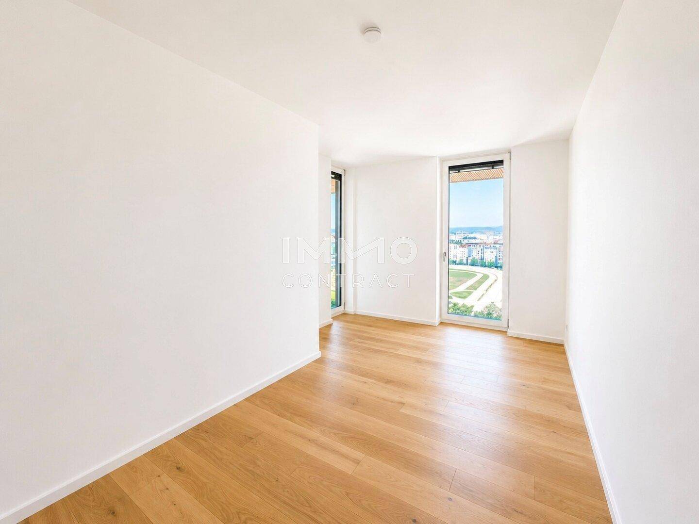 Helles Schlafzimmer mit Holzboden und Fenstern, die einen weiten Blick über die Umgebung ermöglichen.