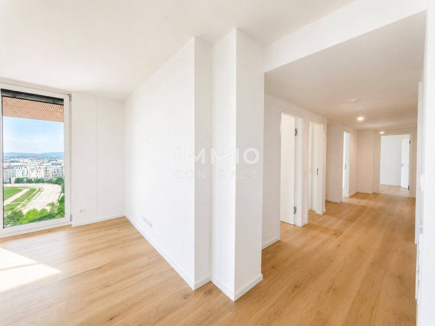 Heller Eingangsbereich mit Holzboden und weißen Wänden, der zu den Wohnräumen führt.
