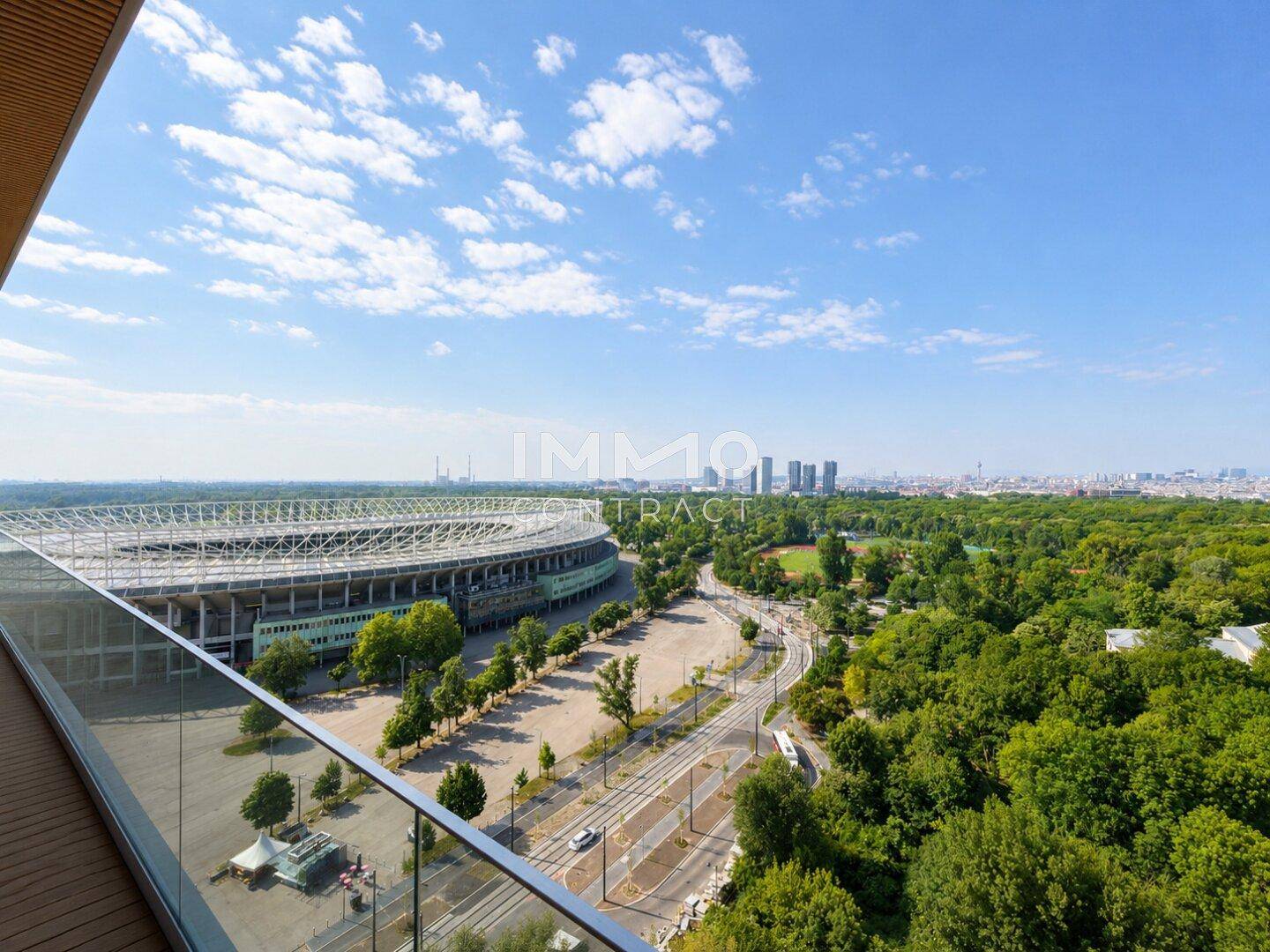 Geräumiger Balkon mit Holzboden und Glasgeländer bietet einen weiten Blick auf das Stadion und die Stadt.