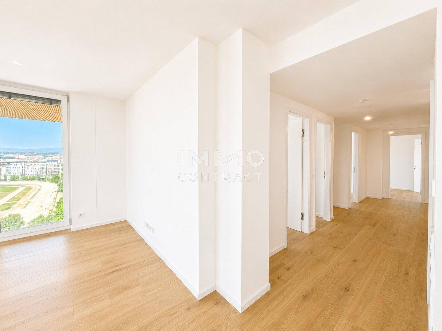 Heller Eingangsbereich mit Holzboden und weißen Wänden, der zu den Wohnräumen führt.
