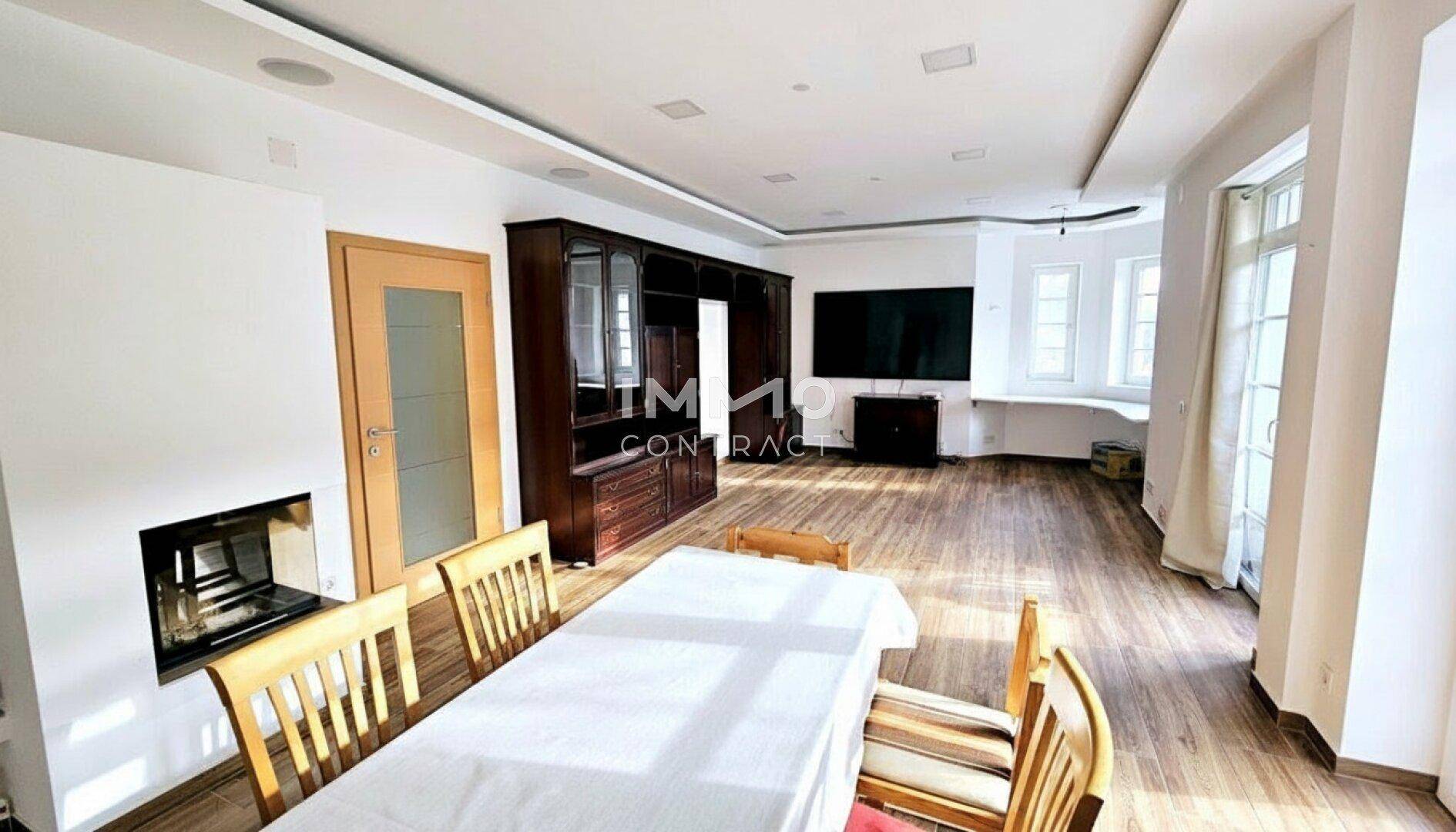 Großer Wohn- und Essbereich mit Holzboden, Kamin und einem eleganten Holzschrank.