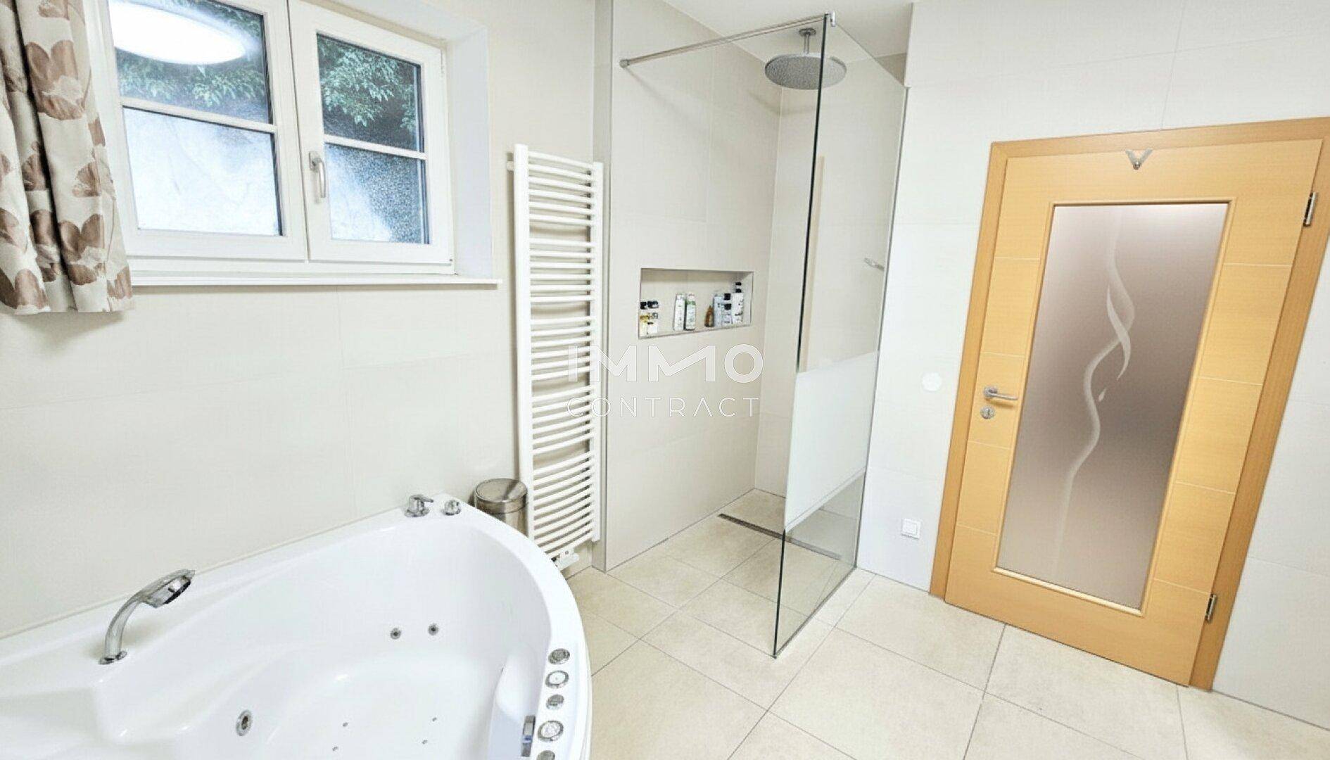 Elegantes Badezimmer mit Eck-Whirlpool, begehbarer Dusche und Handtuchheizkörper.