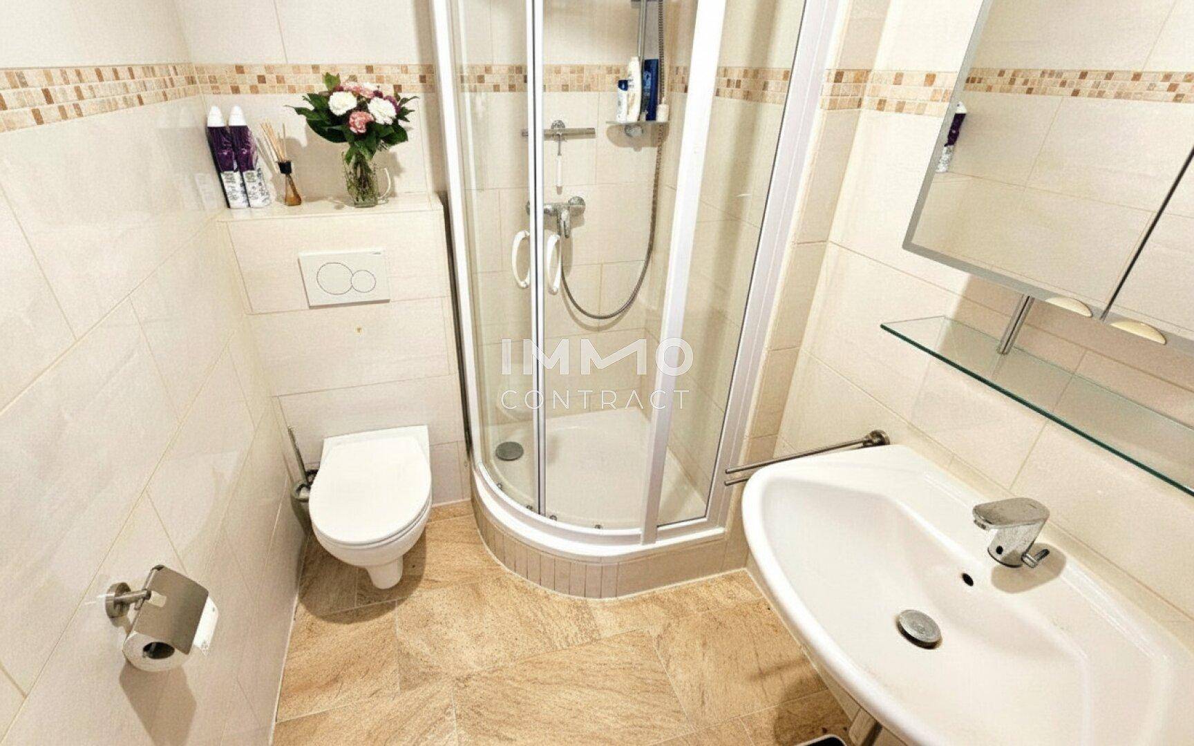Kleines Badezimmer mit Toilette, Waschbecken und Duschkabine, funktional eingerichtet.
