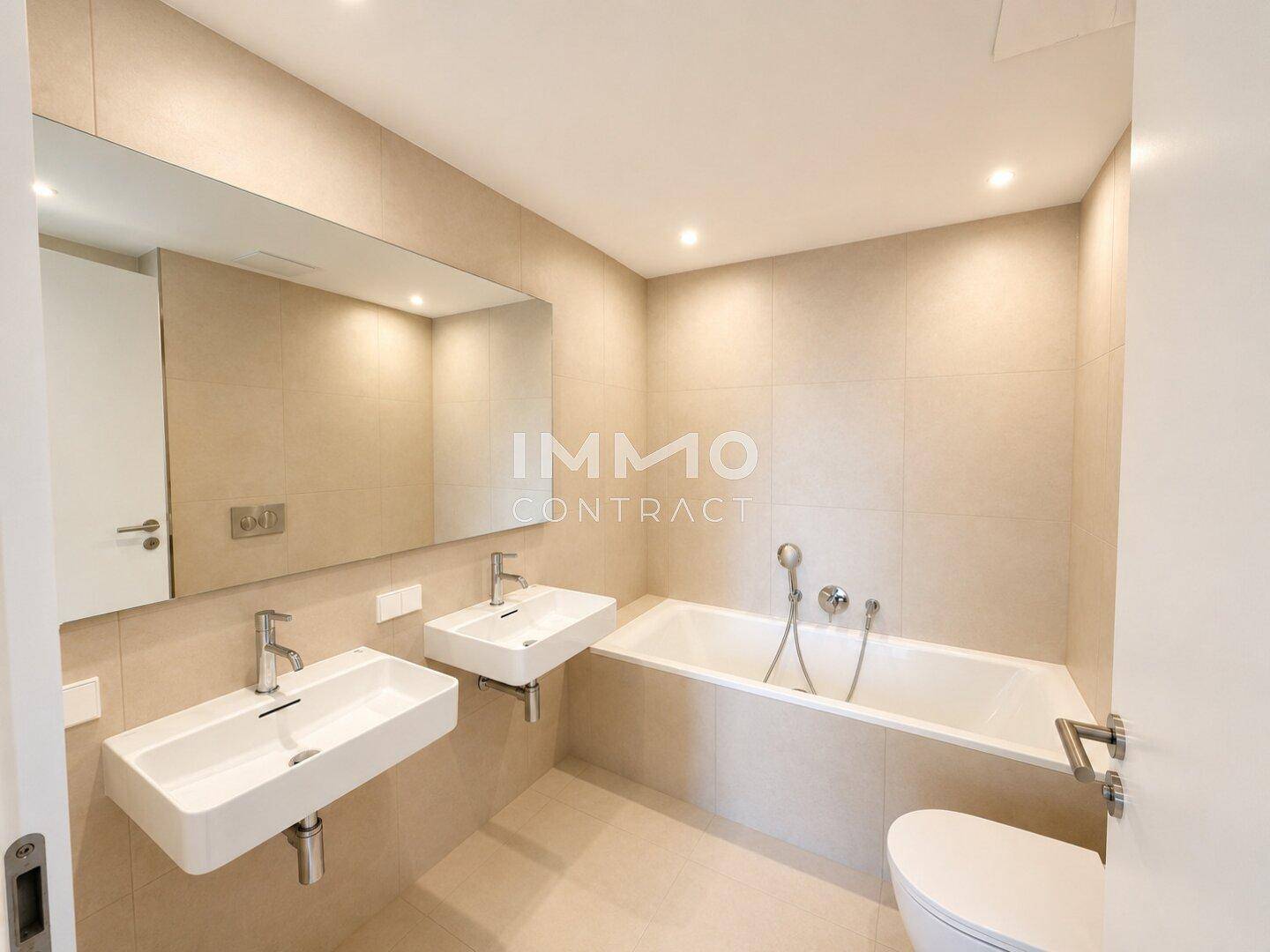 Modernes Badezimmer mit zwei Waschbecken, Badewanne und hellen Fliesen.