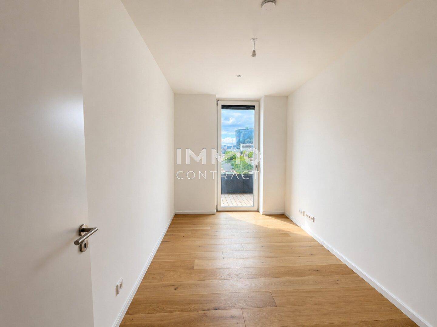 Helles Schlafzimmer mit Parkettboden und Zugang zu einem kleinen Balkon.