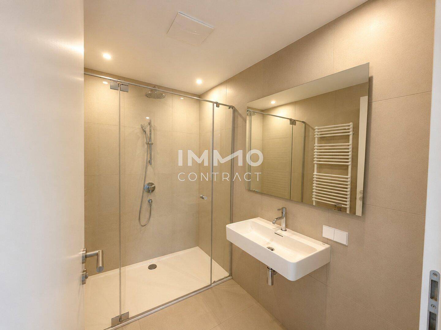 Modernes Badezimmer mit ebenerdiger Dusche, Einzelwaschbecken und beheiztem Handtuchhalter.